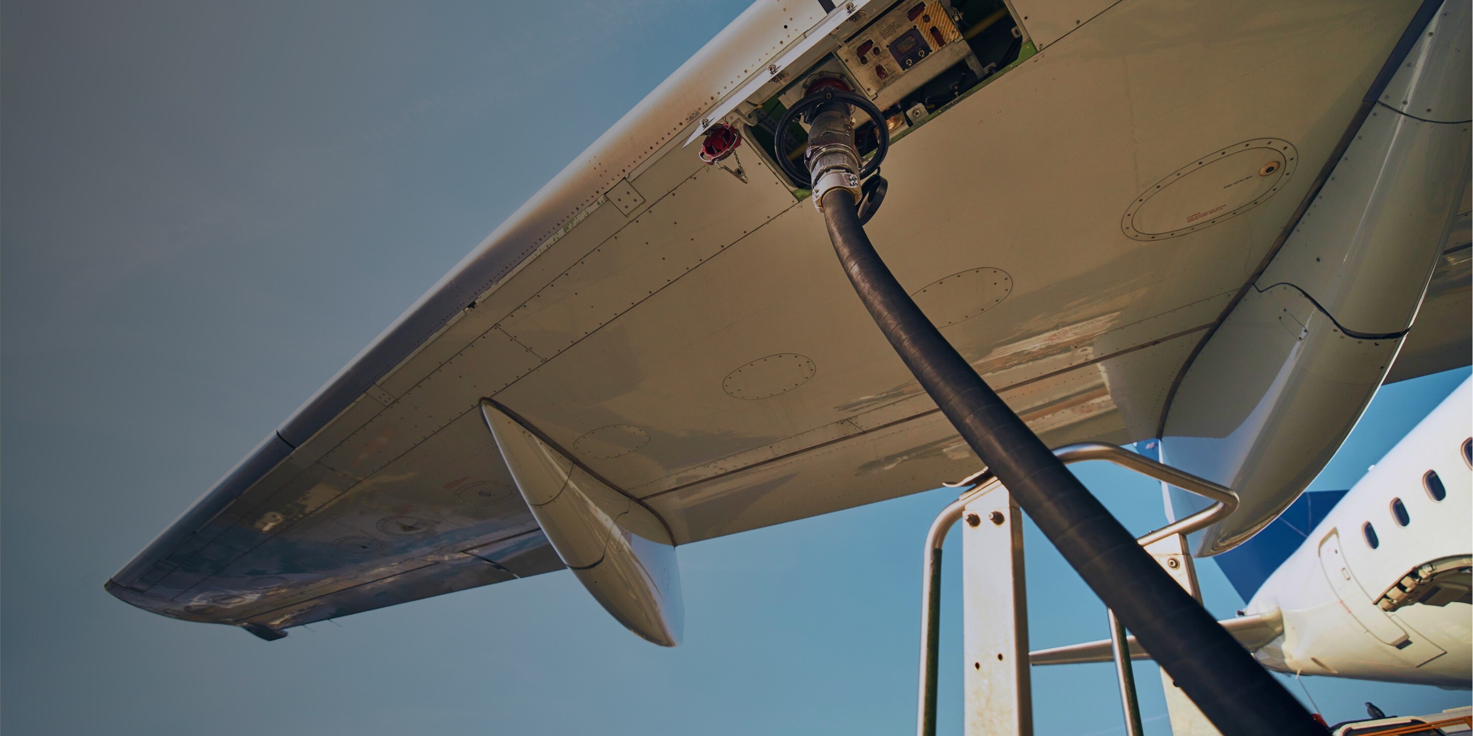 An airplane being filled up with efuel by the wing
